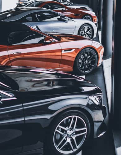 Row of luxury cars including sedans and sports cars parked indoors, representing fleet maintenance service