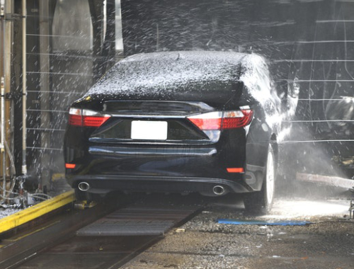 Black car going through an automatic wash with thick white foam, representing Triple Ultra Foam Polish for shine and protection